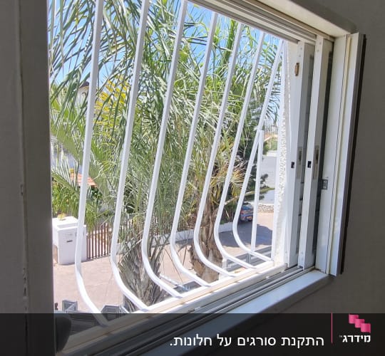 סורגי מתכת לבנים עם בטן המותקנים על חלון בבית